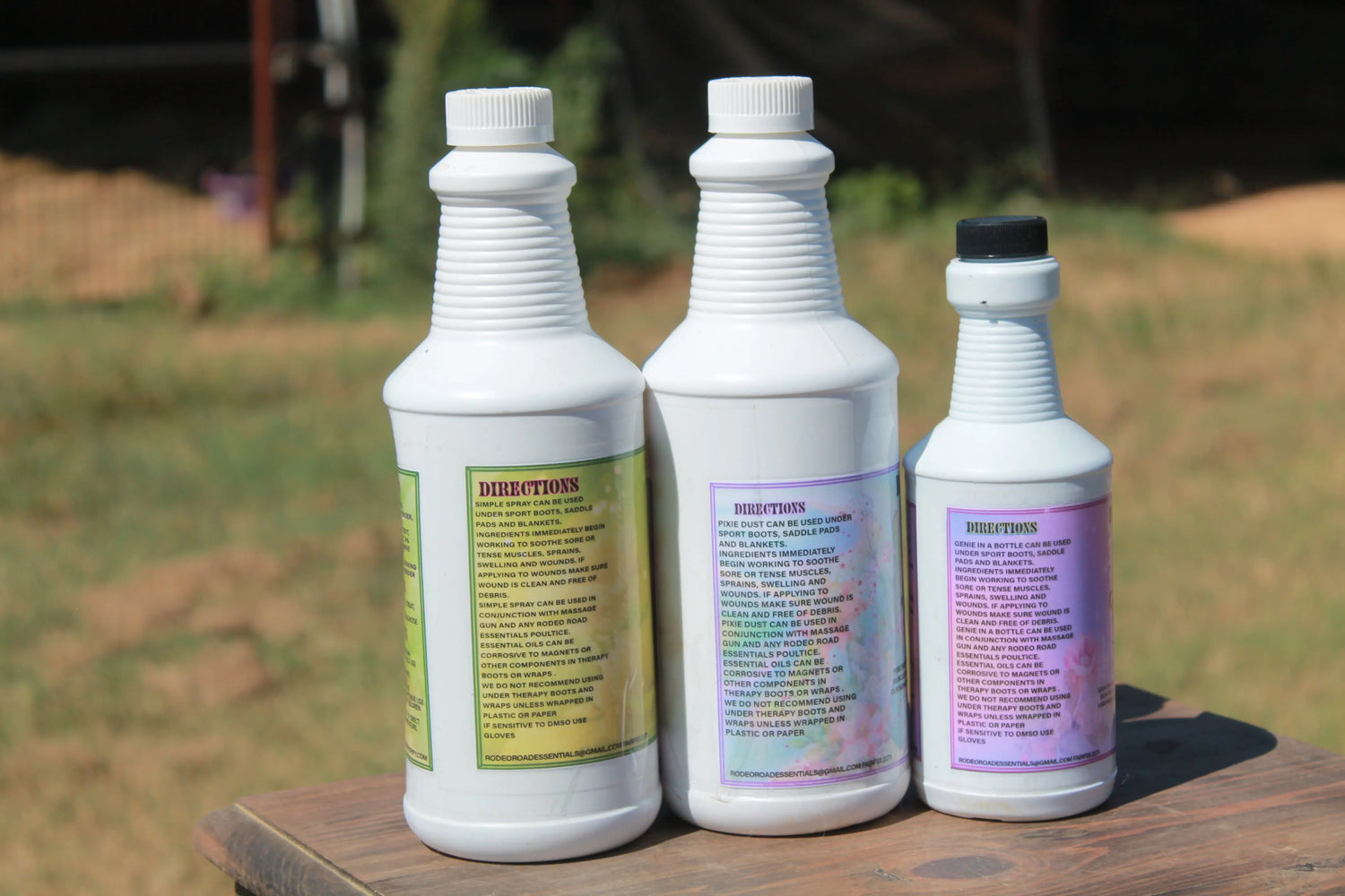 Collection of Rodeo Road Essentials Spray Liniments displayed outdoors, showcasing various bottles including Simple Spray, Genie In A Bottle Spray, and Pixie Dust Spray, ideal for soothing and relieving muscle discomfort in horses.