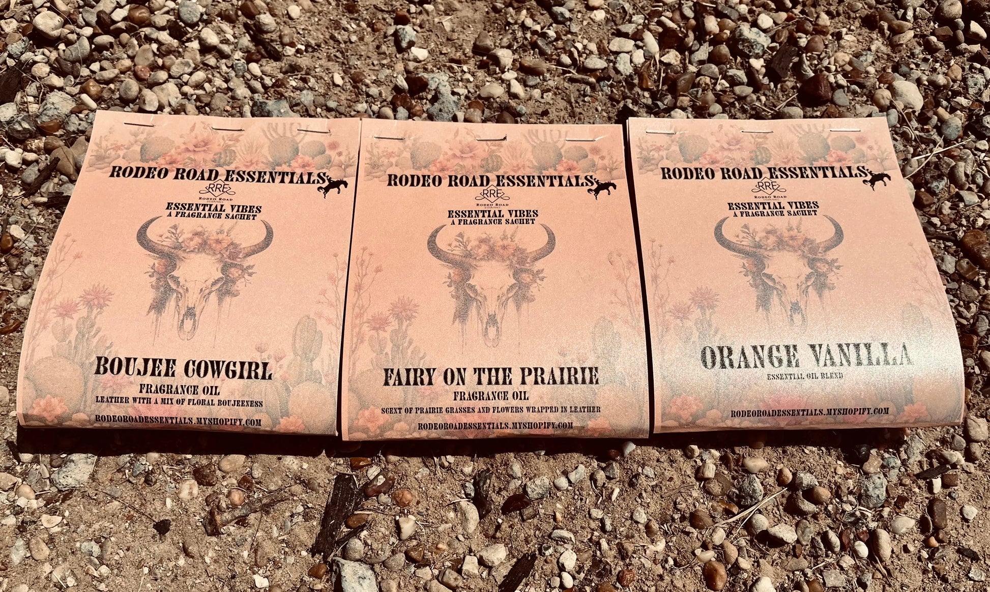 Rodeo Road Essentials Car or Trailer Sachet featuring three distinct scents: Boujee Cowgirl, Fairy on the Prairie, and Orange Vanilla, displayed against a rustic gravel background.